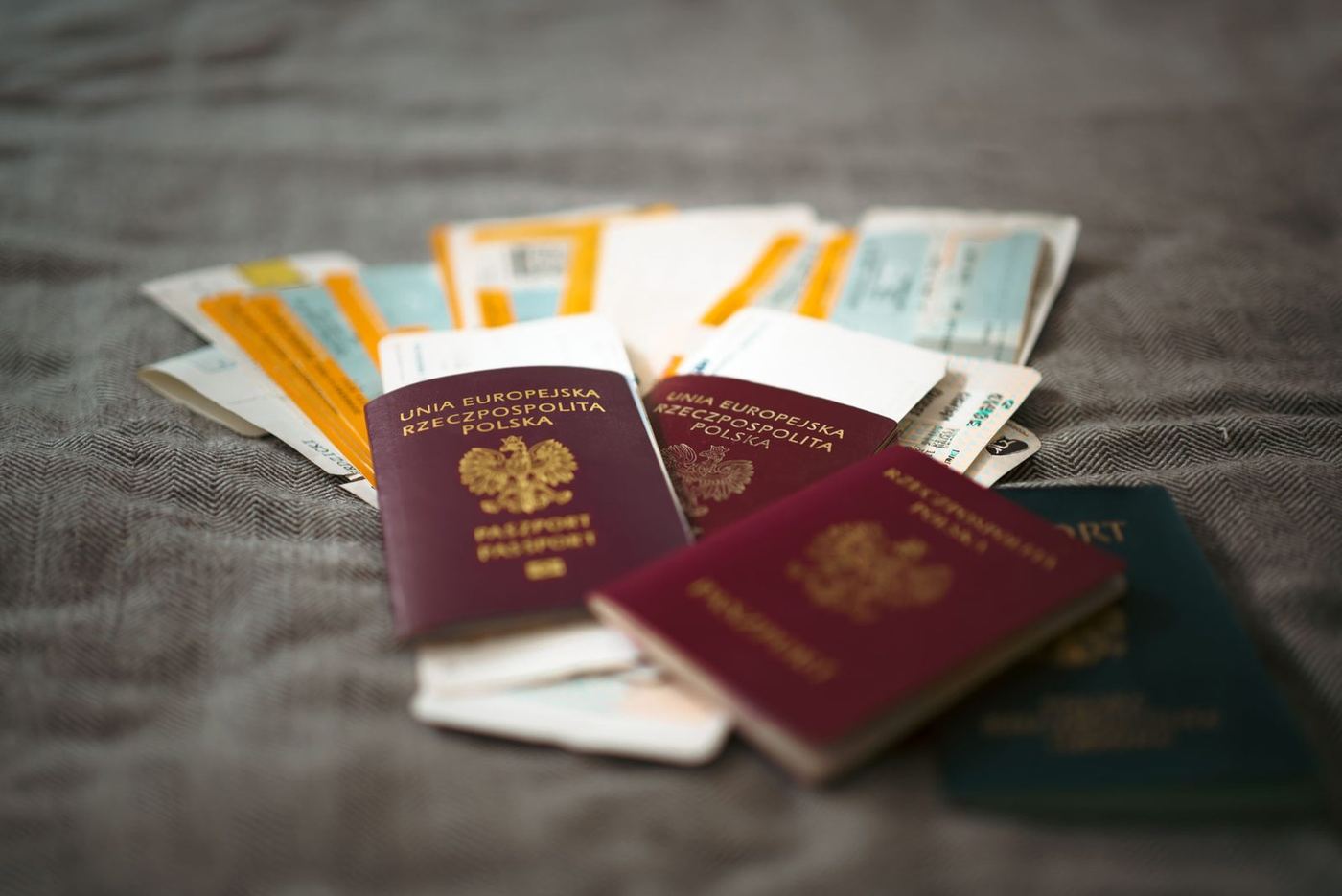 A maroon Polish passport and airline boarding passes arranged on a textured grey-brown surface, with the crowned Polish eagle and gold lettering visible on the cover.